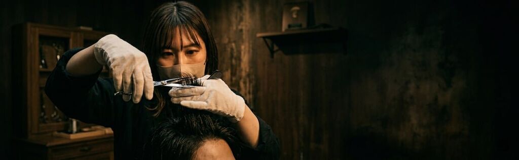 Close-up of hands cutting hair with professional Mina hair cutting scissors in a dark studio setting