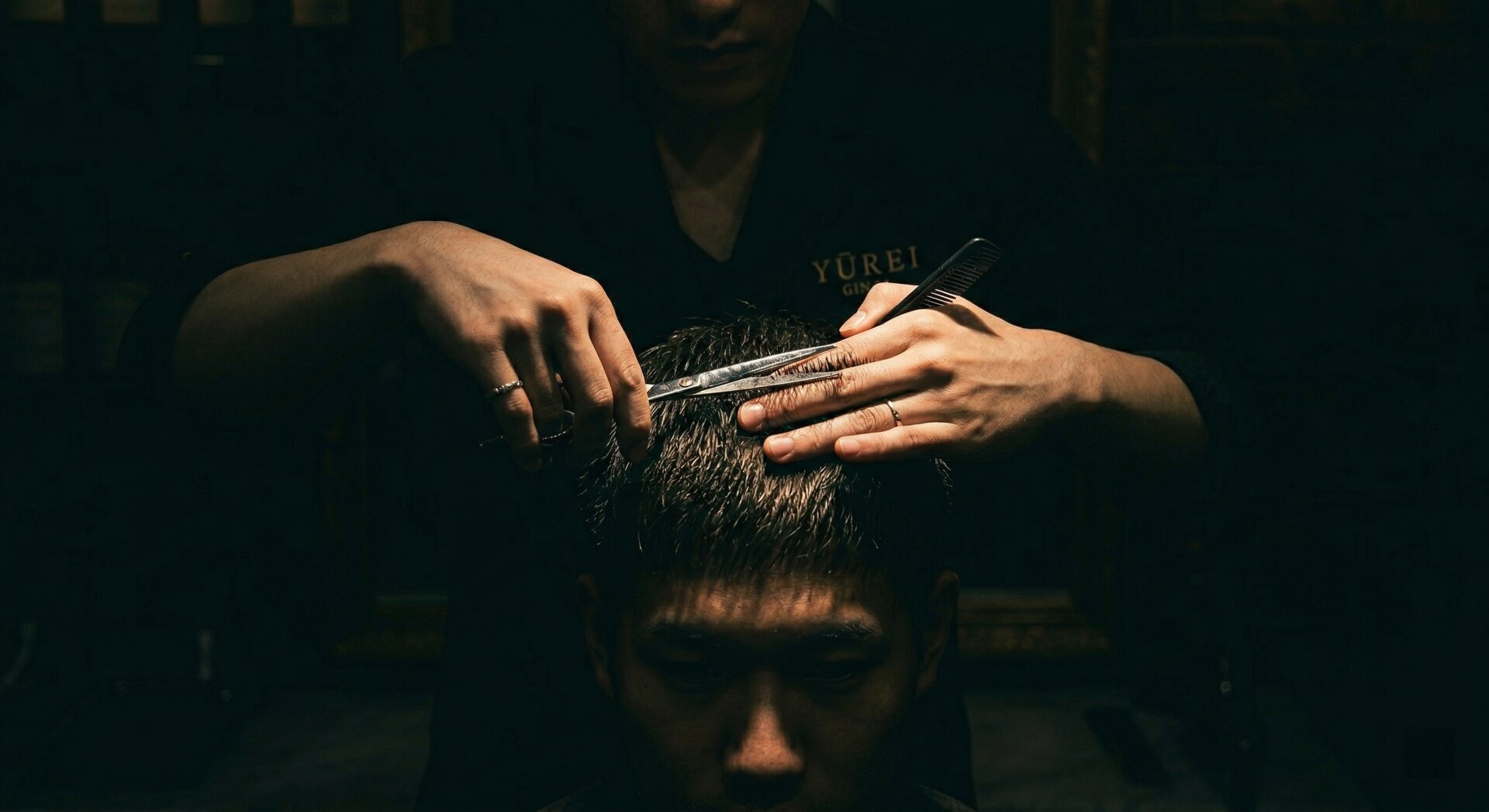 Professional male barber cutting a customer's hair with dark studio dramatic lighting