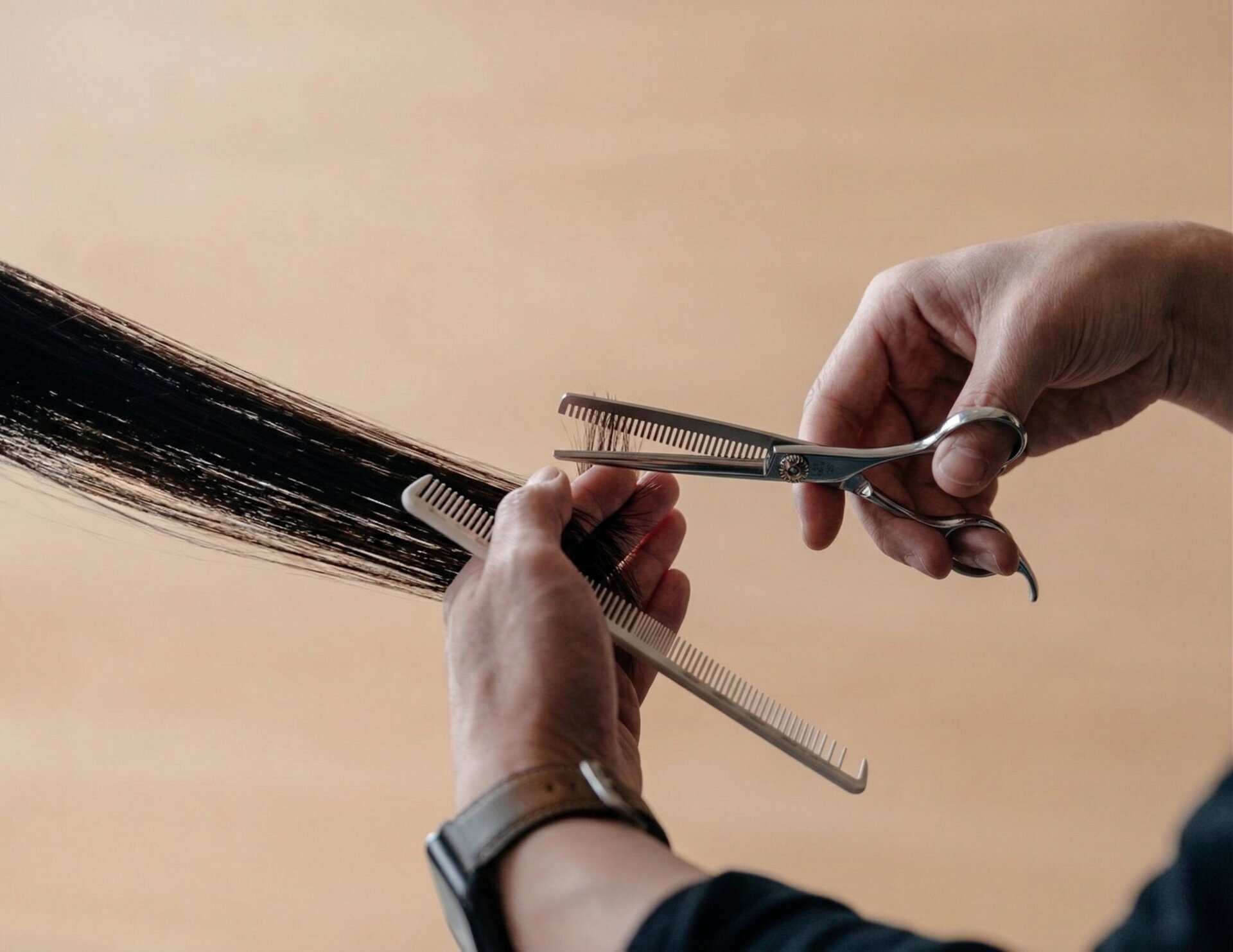 Mina Barber thinning shears held in professional hands with warm studio lighting